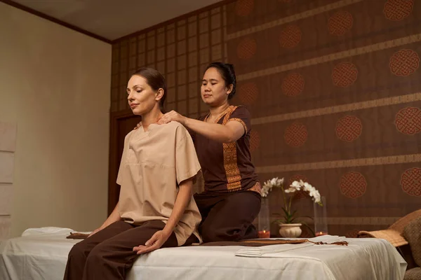 Calm patient massaged in seated position by professional masseuse — Stock Photo, Image