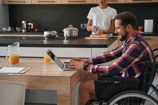 Adorável caucasiano mensagem de digitação masculina no notebook no quarto moderno dentro de casa — Fotografia de Stock