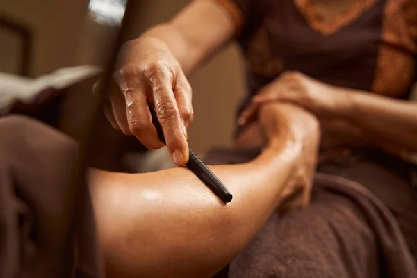 Ervaren masseuse met houten gereedschap tijdens traditionele Thaise voetmassage — Stockfoto