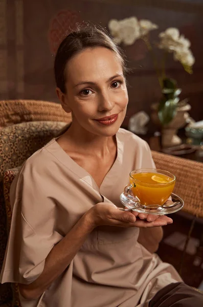 Serene spa client met kruidendrank zittend in rieten fauteuil — Stockfoto