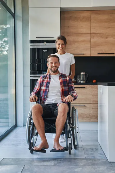 Bedårande man som använder rullstol och charmig kvinna poserar vid fotokameran i huset — Stockfoto