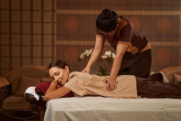 Experienced massotherapist giving female patient Thai massage — Stock Photo, Image