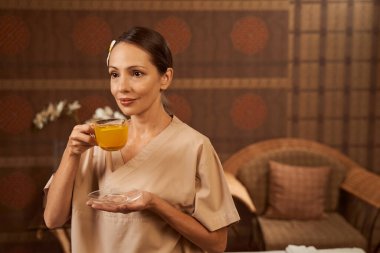 Elinde bitkisel içecekle sakin bir spa müşterisi.