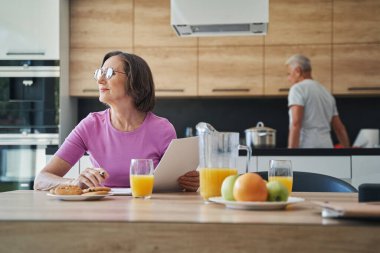 Yaşlı iş kadını belgeye sırtını dönüp pencereden içeri bakıyor.