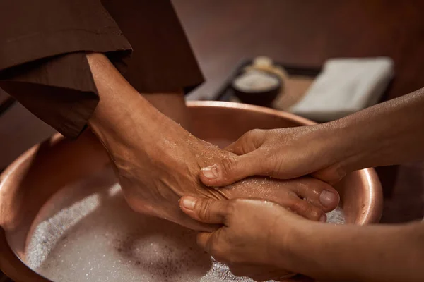 Опытная массажистка делает клиенту массаж ног — стоковое фото