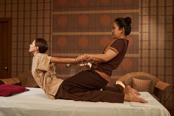 Practitioner stretching her client back muscles during Thai massage session — Stock Photo, Image