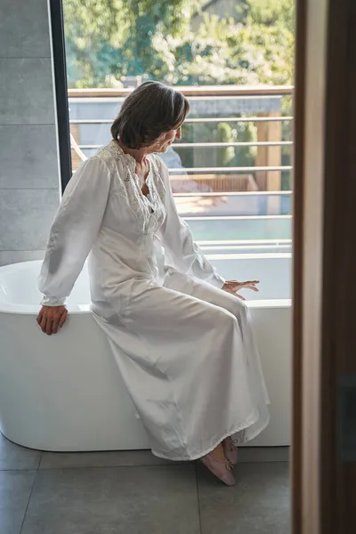 Femme retraitée assise sur le bord du bain — Photo