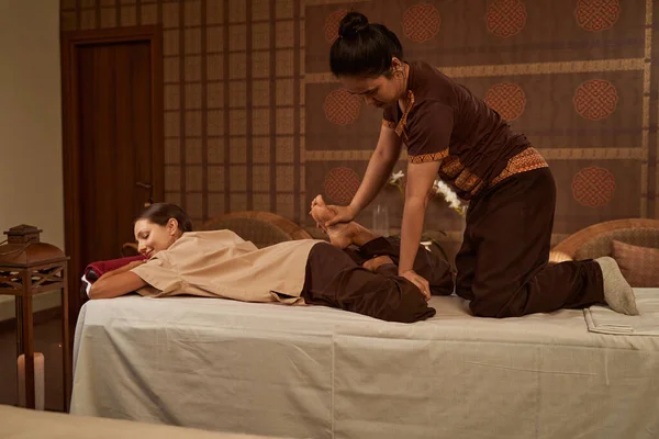 Thai massage practitioner performing reverse half lotus stretch — Stock Photo, Image