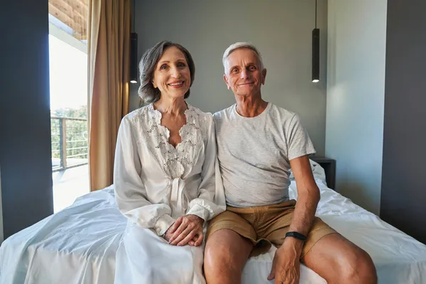 Esposos envelhecidos na cama de casal olhando para a câmera — Fotografia de Stock