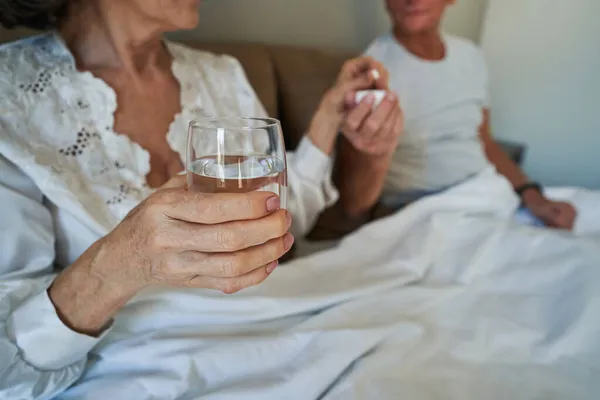Seniorin redet Pille, während sie Glas Wasser hält — Stockfoto