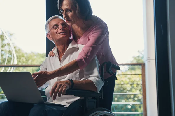 Senior man med funktionshinder vänder sig till sin fru bakom honom — Stockfoto