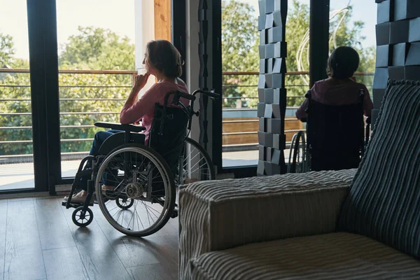 Niepełnosprawna kobieta siedząca głęboko w myślach na wózku inwalidzkim — Zdjęcie stockowe
