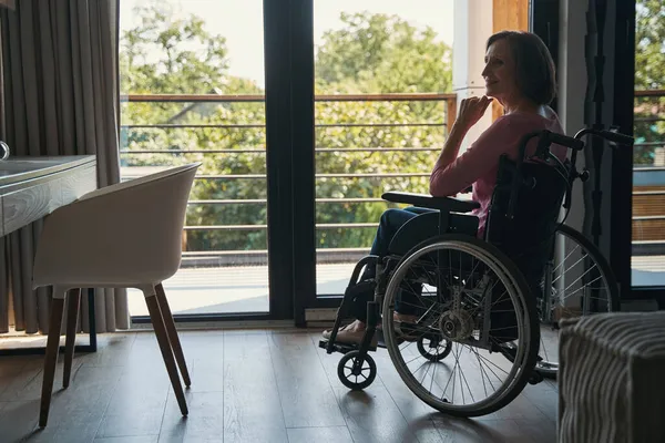 집안에서 휠체어를 타는 여성을 즐겁게 찾는 사람 — 스톡 사진