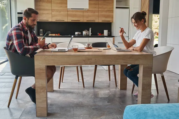 Feliz morena sonriente mujer y hombre guapo trabajando en línea en la cocina — Foto de Stock