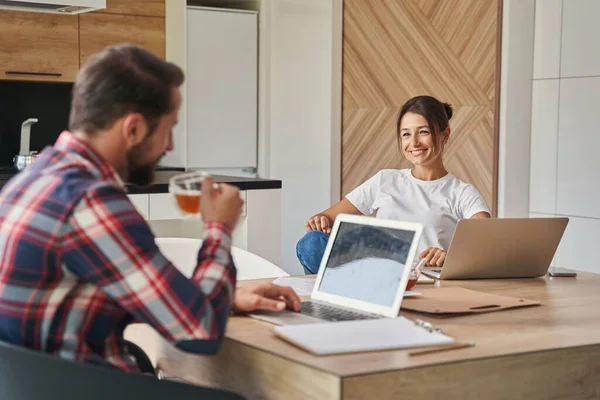 Mulher branca encantadora sentada na mesa de madeira e discutindo com o macho no quarto dentro de casa — Fotografia de Stock