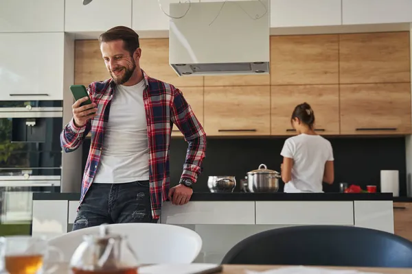 Красивый белый мужчина в футболке, читающий сообщение по мобильному телефону в квартирах — стоковое фото
