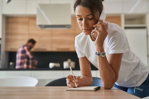 Hermosa mujer caucásica en ropa casual teniendo diálogos en un teléfono móvil en casa —  Fotos de Stock