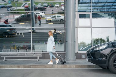 Gülümseyen mutlu turist tramvay çantasını dışarı taşıyor.