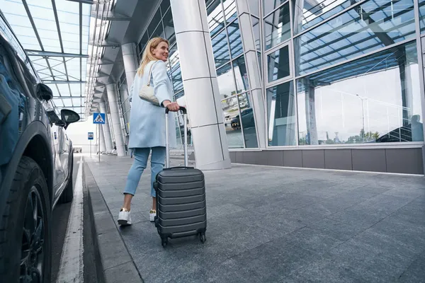 Pleased airline passenger with baggage looking away — Stock Photo, Image