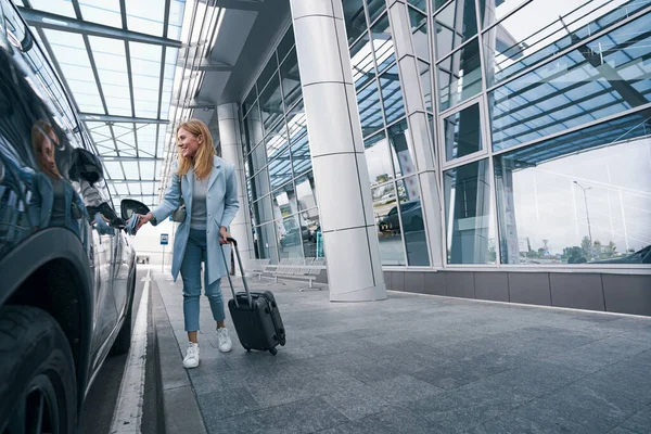 Vreugdevolle toerist met reiskoffer voor taxi 's — Stockfoto