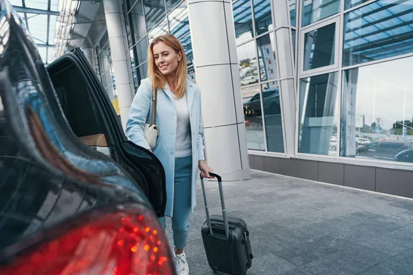 Vrouwelijke passagier met bagage staan voor auto — Stockfoto