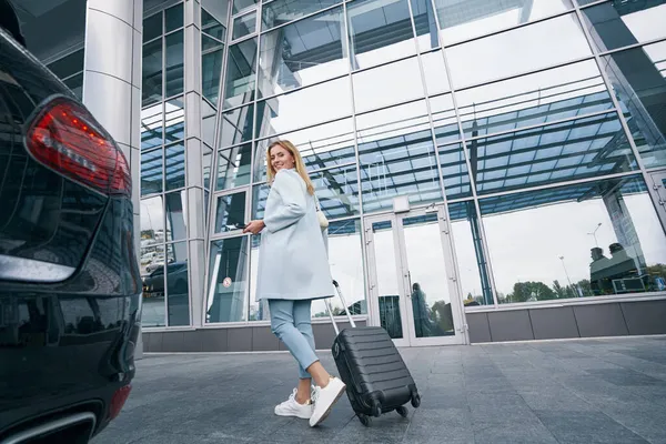 Joyeux voyageur avec valise trolley debout devant le terminal de l'aéroport — Photo