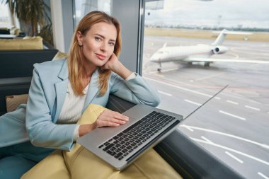 Dizüstü bilgisayarı koltukta oturan sakin bir iş kadını.