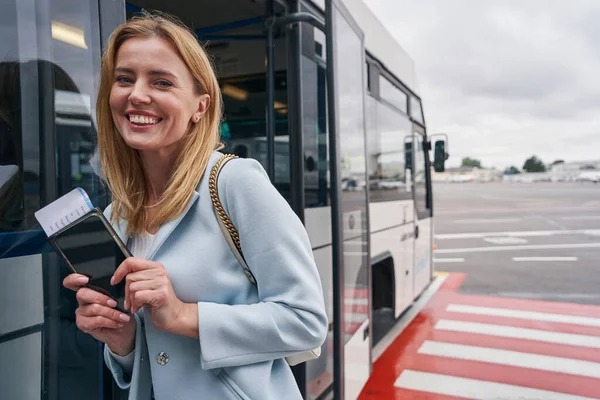 High-spirited tourist posing against beside parked airport shuttle bus — Stock Photo, Image