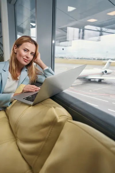 ノートパソコンを持つ女性が空港ラウンジに座っている — ストック写真