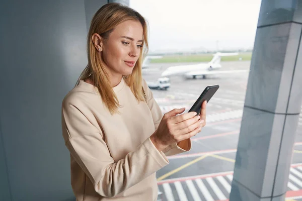 Koncentrerad turist använder sin mobiltelefon i väntrummet — Stockfoto