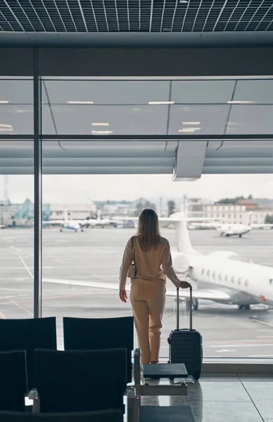 Touristin mit Gepäck steht im Wartebereich des Flughafens — Stockfoto