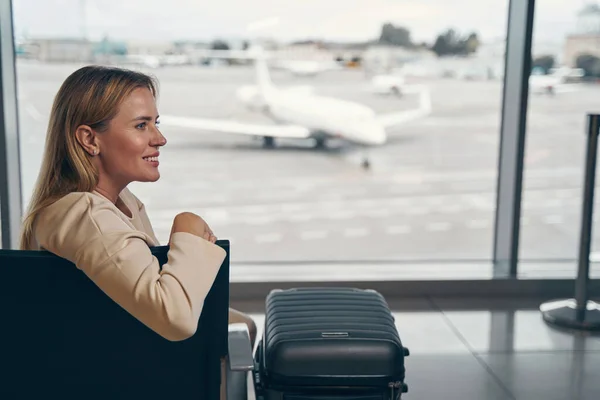 Wesoły turysta siedzi w salonie lotniska przed wejściem na pokład — Zdjęcie stockowe