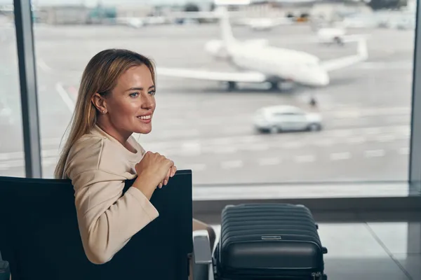 Gelukkige vrouwelijke toerist dagdromen in luchthaven lounge — Stockfoto