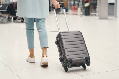 Uçak yolcusu, havaalanı terminalinde bagajları taşıyor.