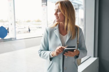 Neşeli, şık bayan yolcu mesafeye bakıyor.