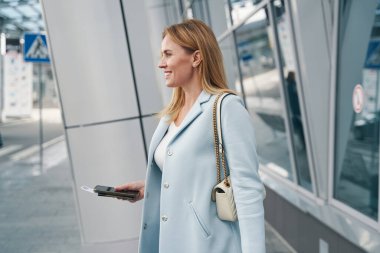 Seyahat belgesi olan memnun yolcu havaalanı terminalinin yanında bekliyor.