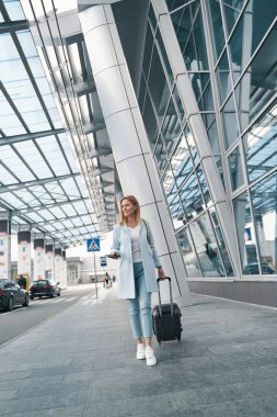 Neşeli, şık, bagajlı, başka tarafa bakan yolcu.