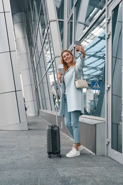 Fröhlicher Passagier fotografiert sich in der Nähe des Flughafengebäudes — Stockfoto