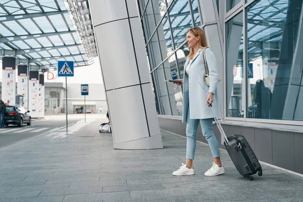Turista de alto espírito com bagagem e documento de viagem olhando para a distância — Fotografia de Stock