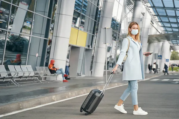 Passager élégant avec bagages s'éloignant du bâtiment de l'aéroport — Photo