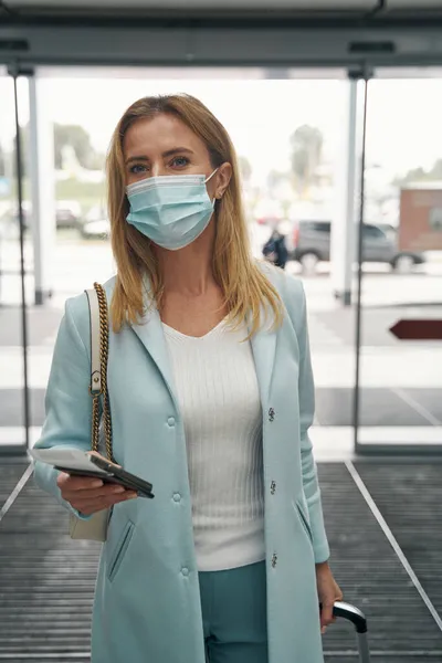 Pasajero con máscara médica con documento de viaje en una mano — Foto de Stock
