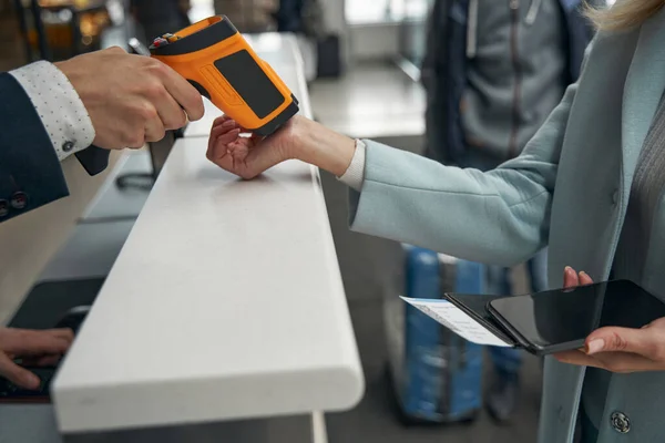 Pracownik portu lotniczego mierzący temperaturę pasażera za pomocą bezdotykowego cyfrowego urządzenia ręcznego — Zdjęcie stockowe