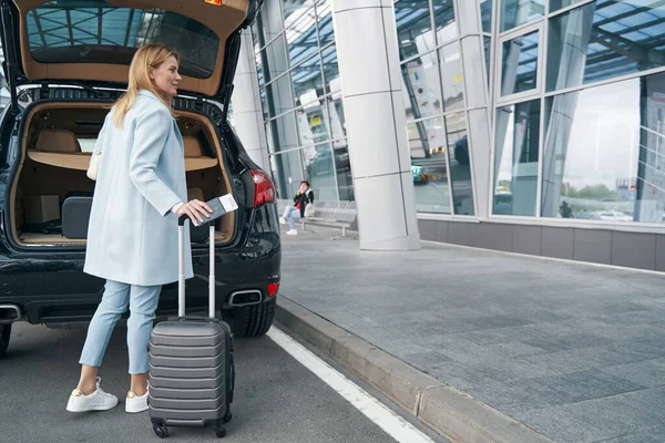 Passagier mit Reisedokument und Gepäck in der Nähe des offenen Kofferraums — Stockfoto