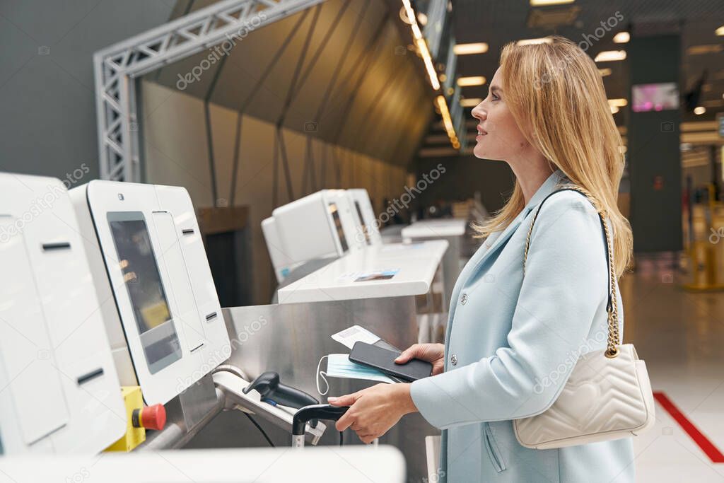 Pleased passenger with travel documents and luggage staring into distance