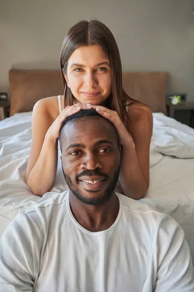 Fiatal nő fekszik az ágyon mögött boldog férfi — Stock Fotó