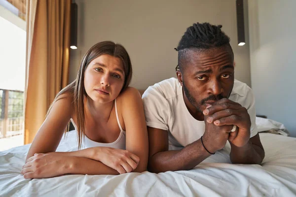 Mixed-race couple ignoring each other in bedroom — Stock Photo, Image