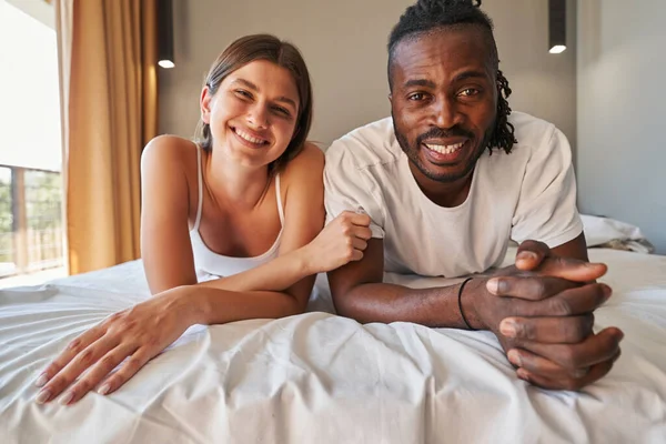 Happy romantic mixed-race couple resting in bed — Stock Photo, Image