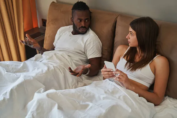Mladý smíšené rasy pár vede rozhovor v ložnici — Stock fotografie