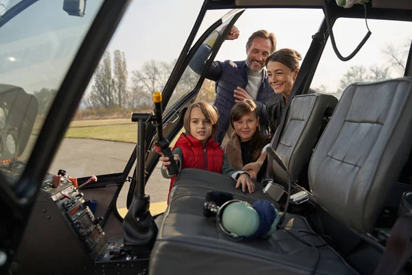 Açık bir helikopter kokpitinin yanında poz veren neşeli bir aile. — Stok fotoğraf
