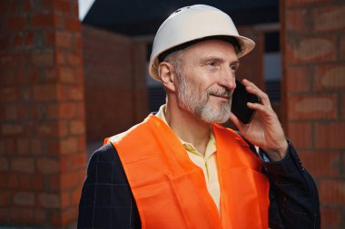 Üniformalı yaşlı adam telefon görüşmesi yapıyor.